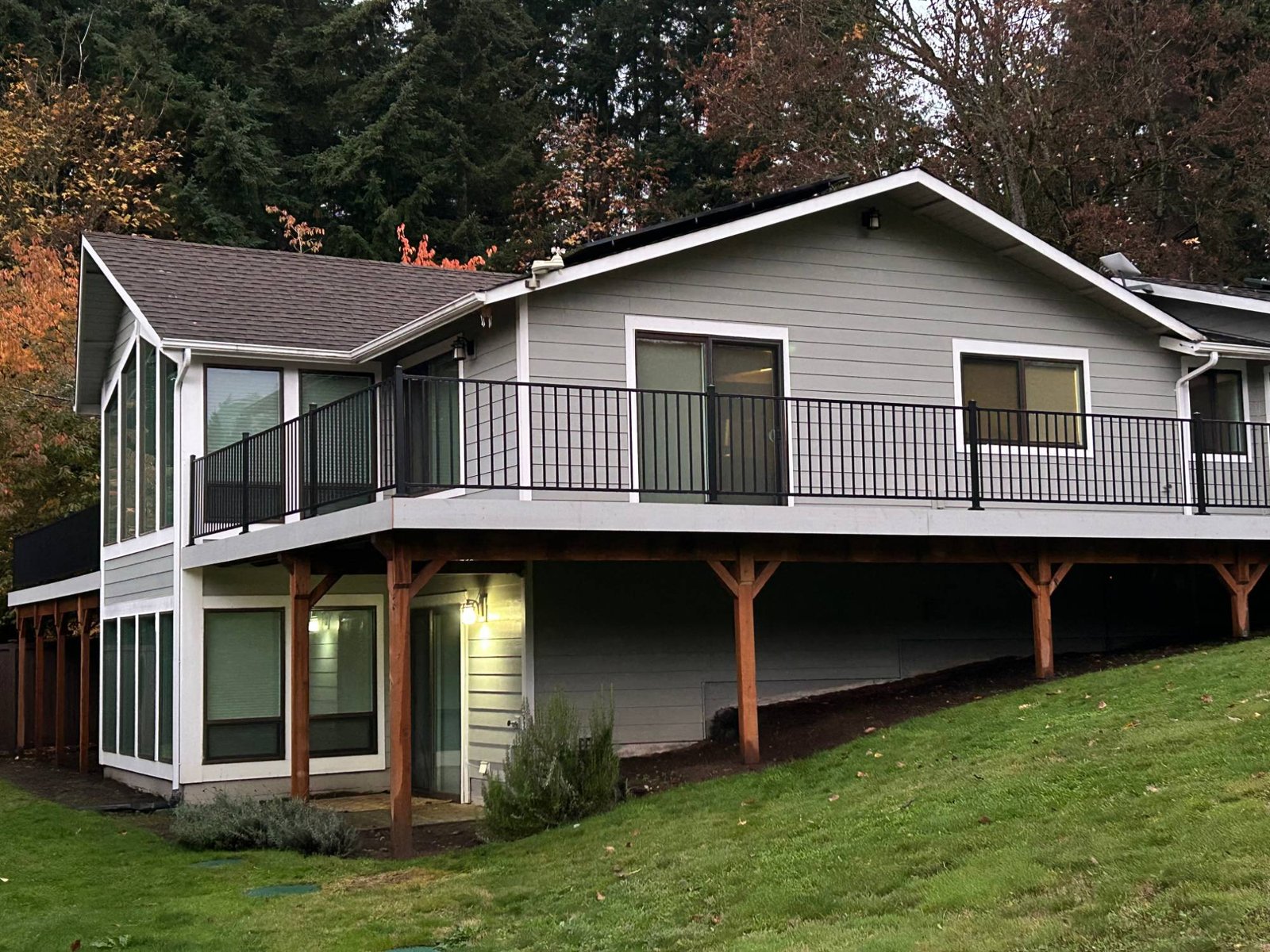 Rebuilt elevated deck with black metal railings on a grey-sided home