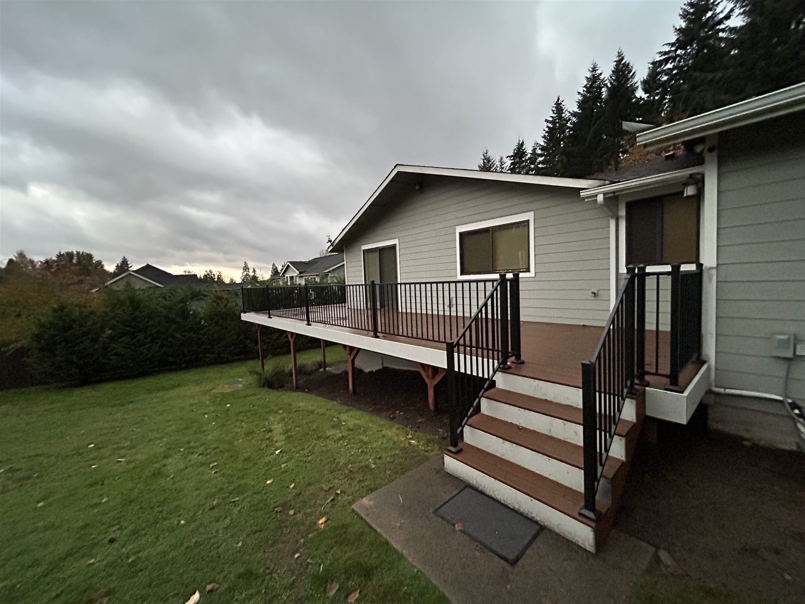 After: new deck stairs with black metal railings leading down to the lawn