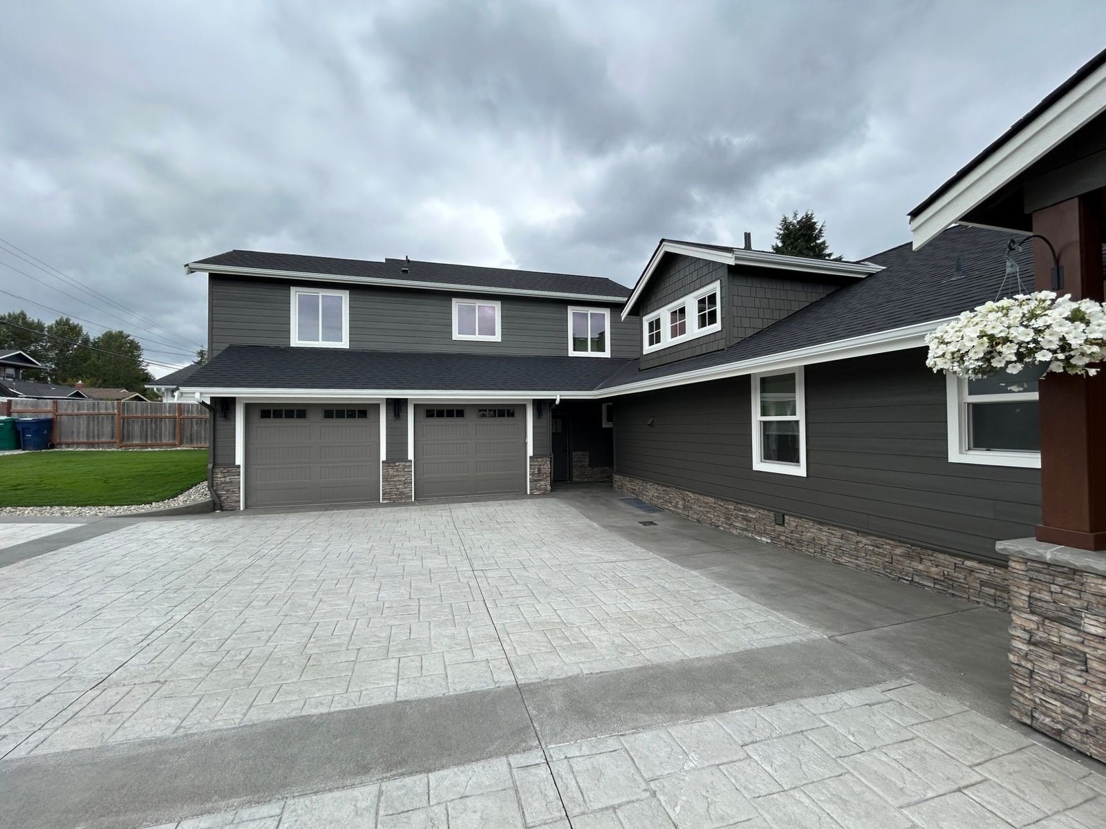 After: garage wing with carriage-style doors and a stone veneer base above the stamped driveway