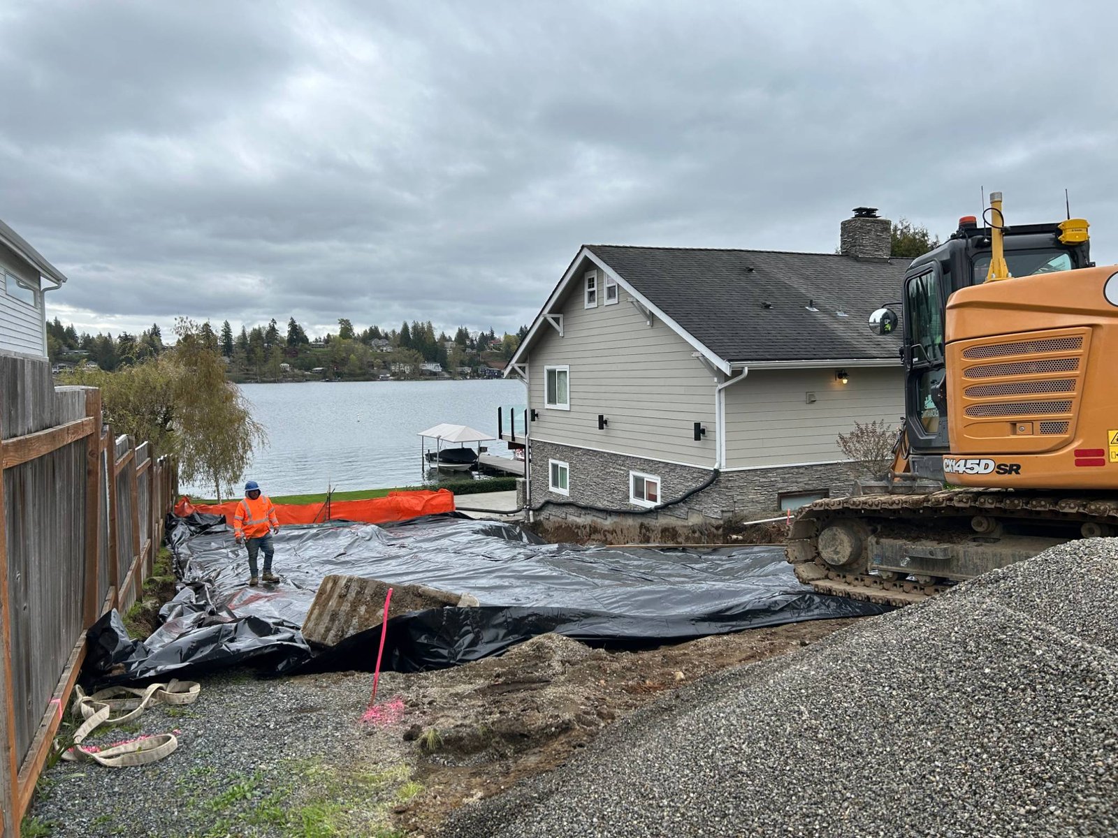 During: site prep on the lakefront lot, with an excavator, gravel and poly sheeting