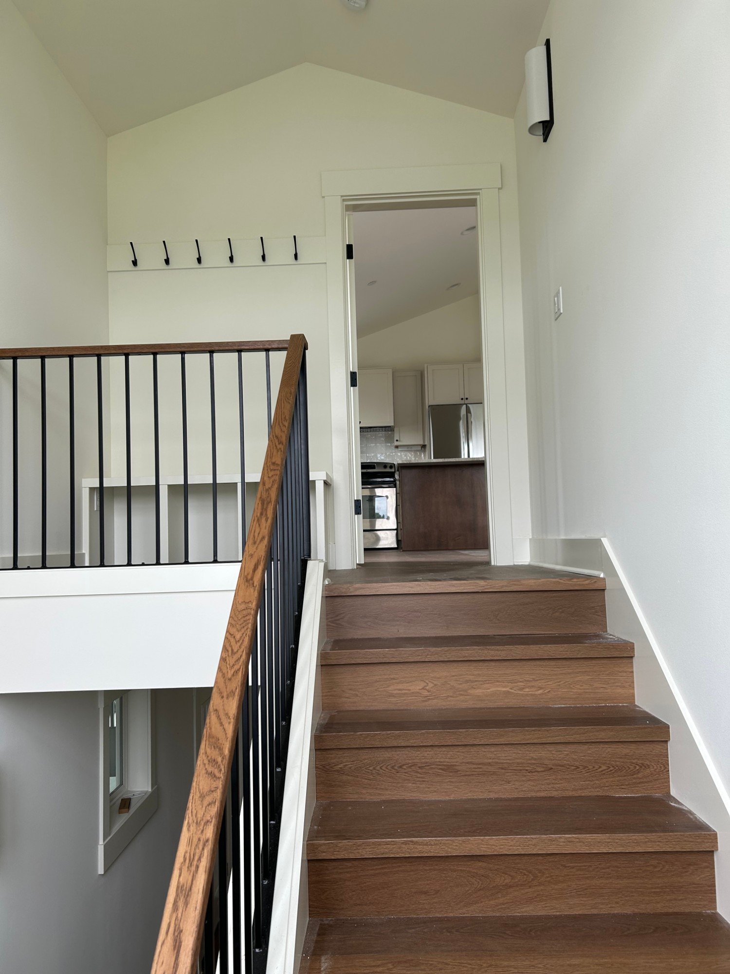 Wood stairs with black metal balusters leading up to the kitchen