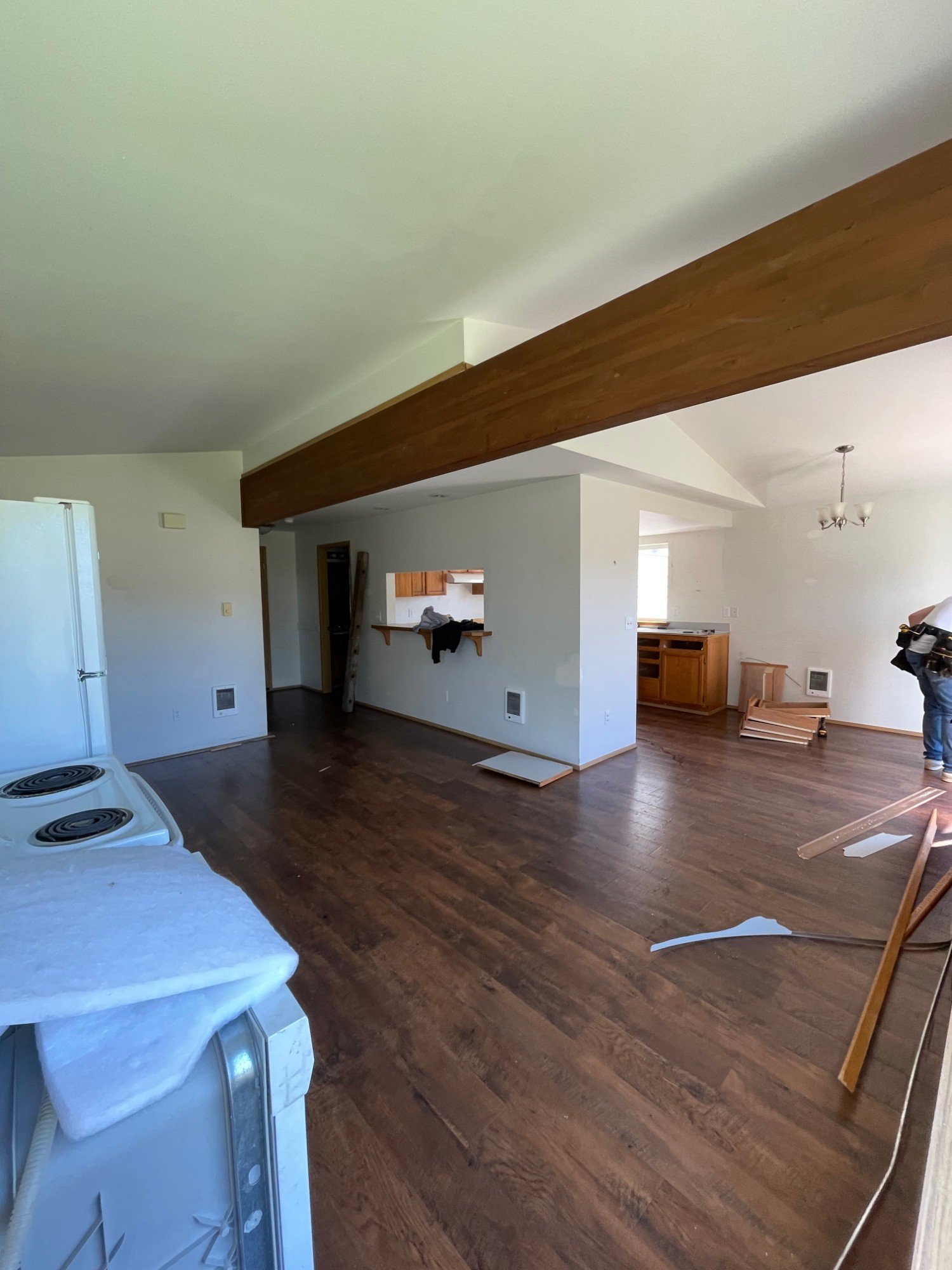 Before: living area with dark floors, stained beam and walled-off kitchen