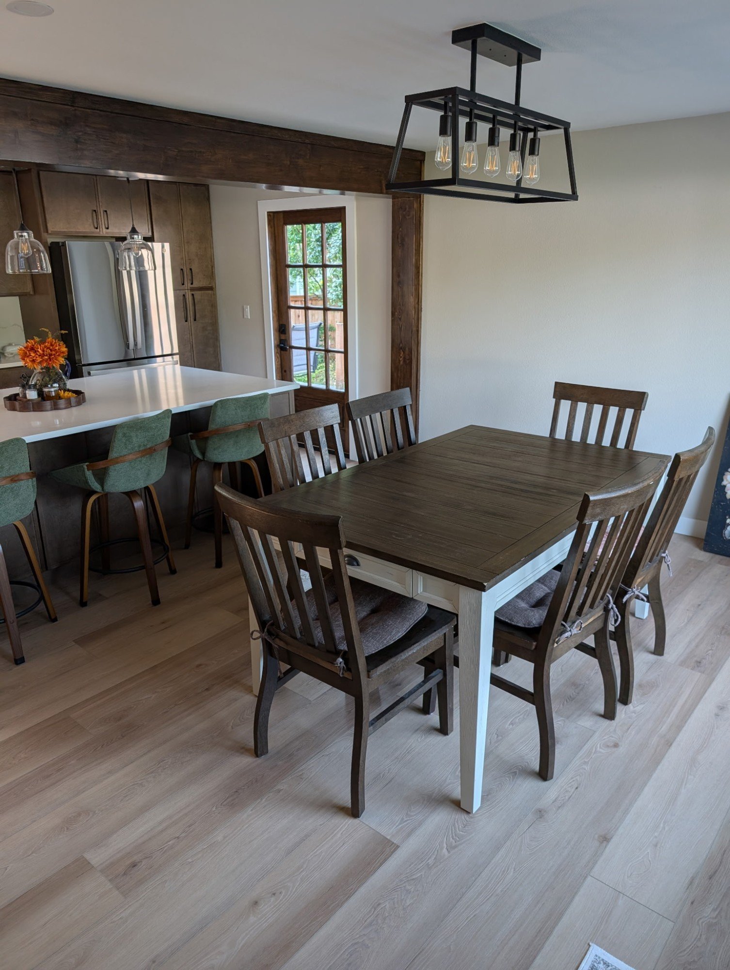 Dining area with a black cage chandelier next to the kitchen island