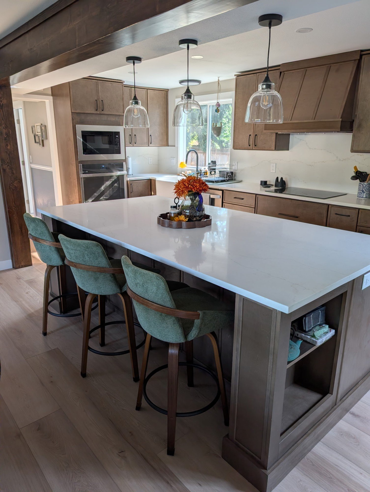 Kitchen island with green stools under glass pendant lights