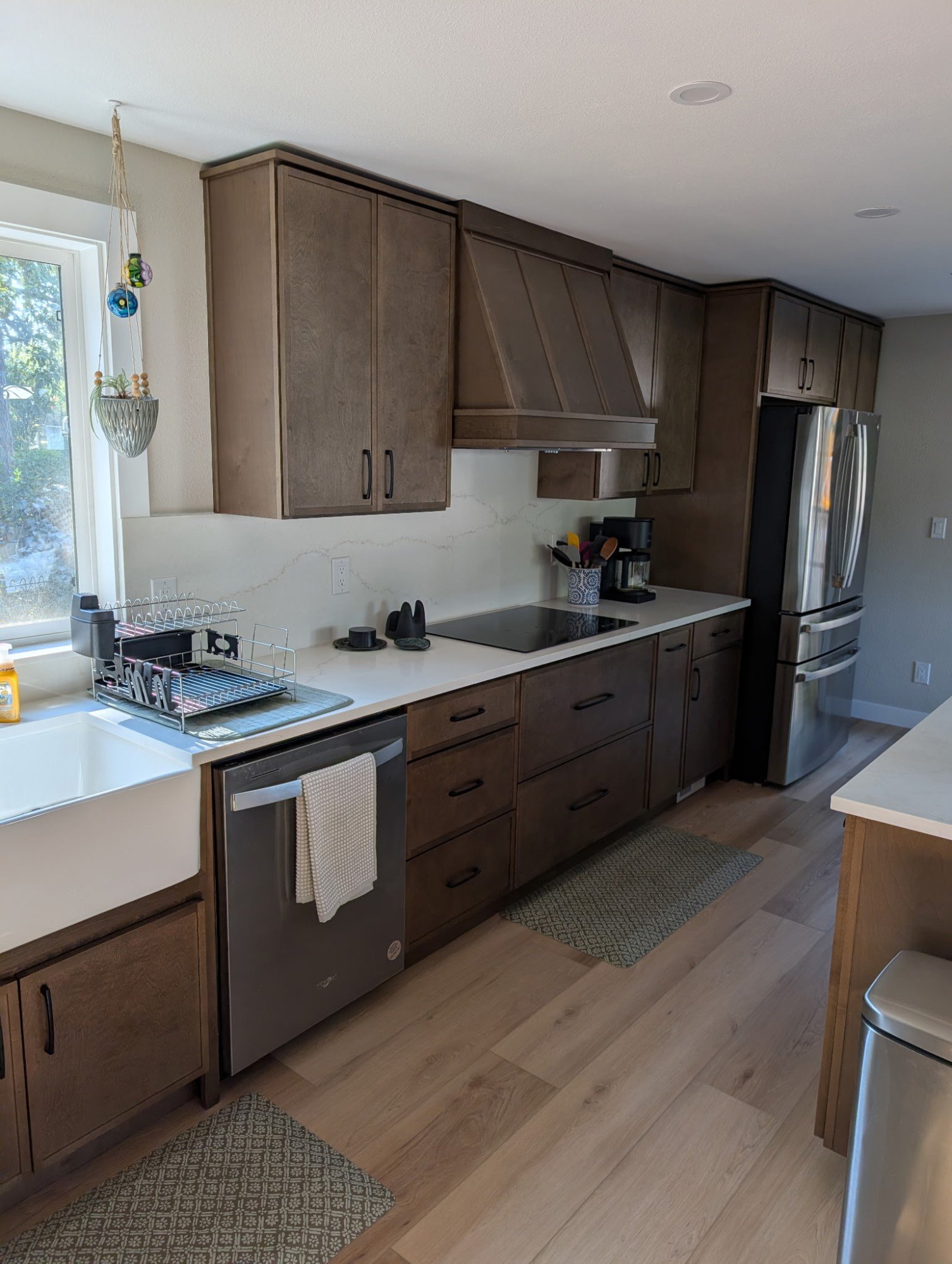 Cabinet run with induction cooktop, wood range hood and quartz backsplash