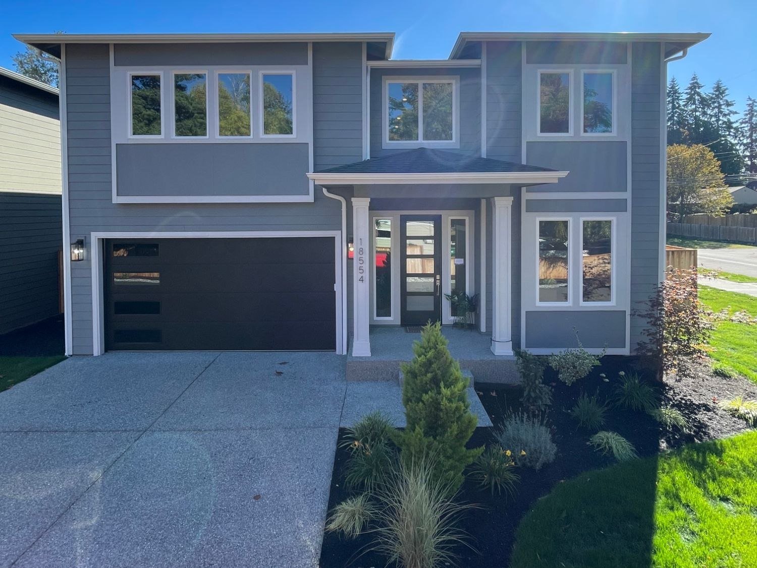 Front of the new Stone Ave home in Shoreline with grey lap siding and a black garage door