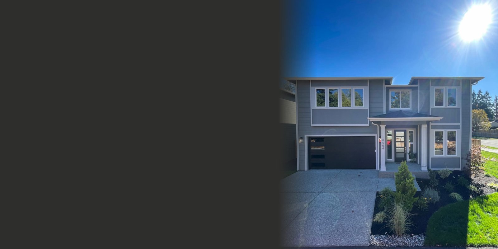 New two-story home on Stone Ave N in Shoreline with grey lap siding, white trim, a black garage door and fresh landscaping