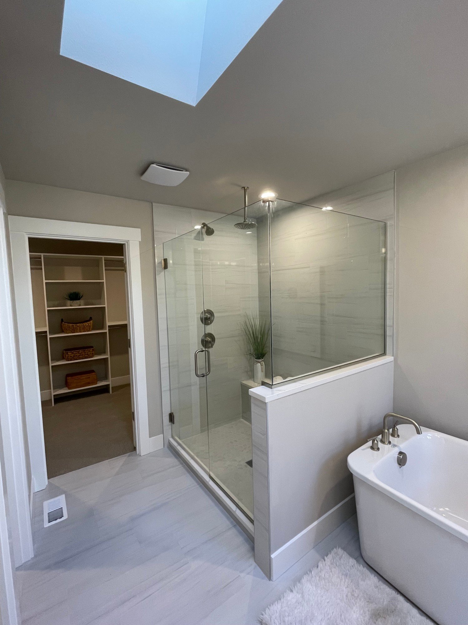 Frameless glass shower with a rain head and tile bench, next to the walk-in closet