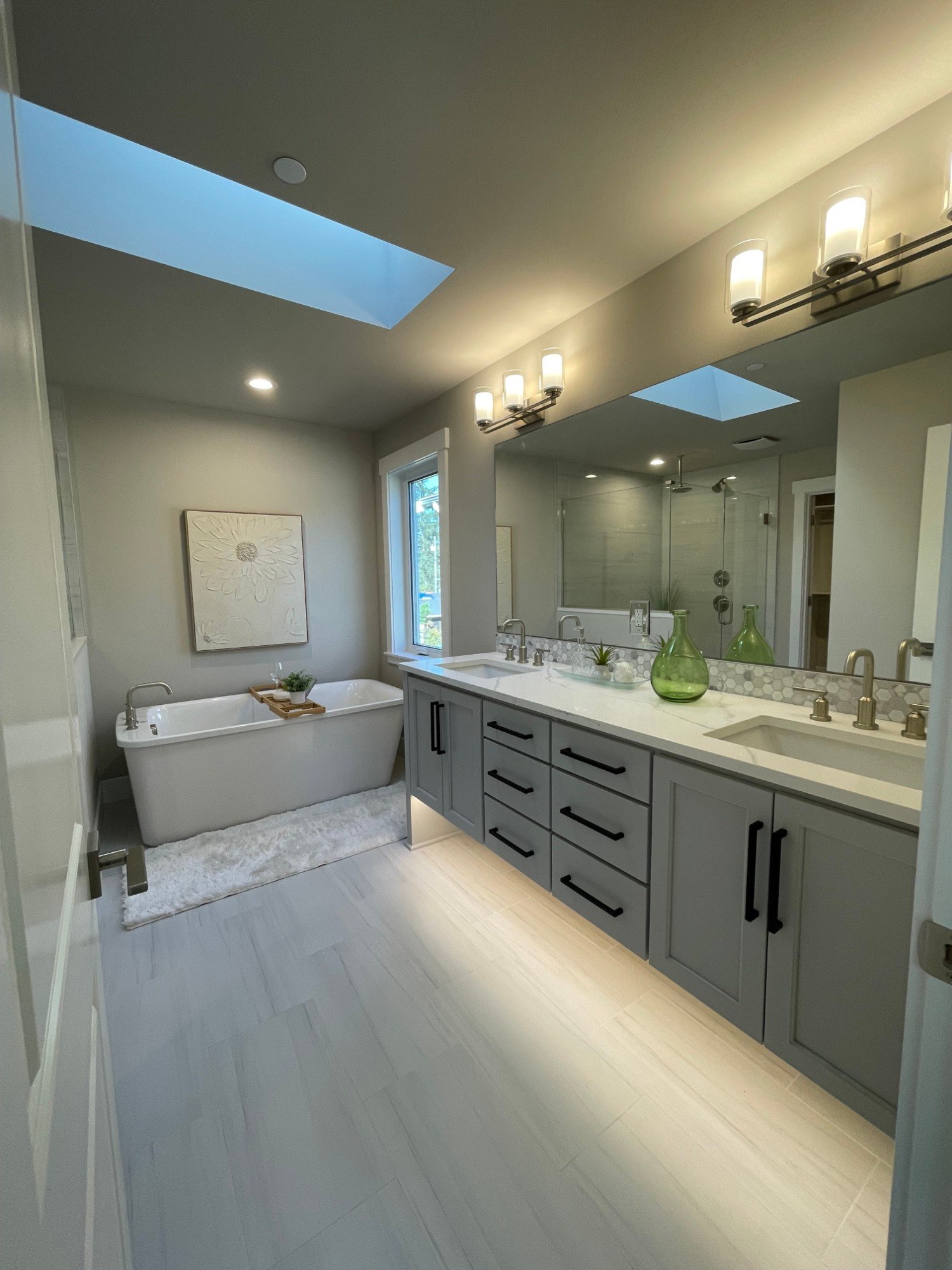 Primary bath with a skylight, freestanding tub and a floating double vanity with under-cabinet lighting