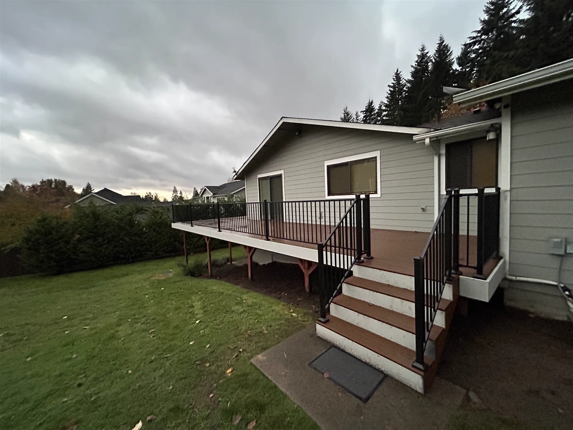 After: new deck stairs with black metal railings leading down to the lawn