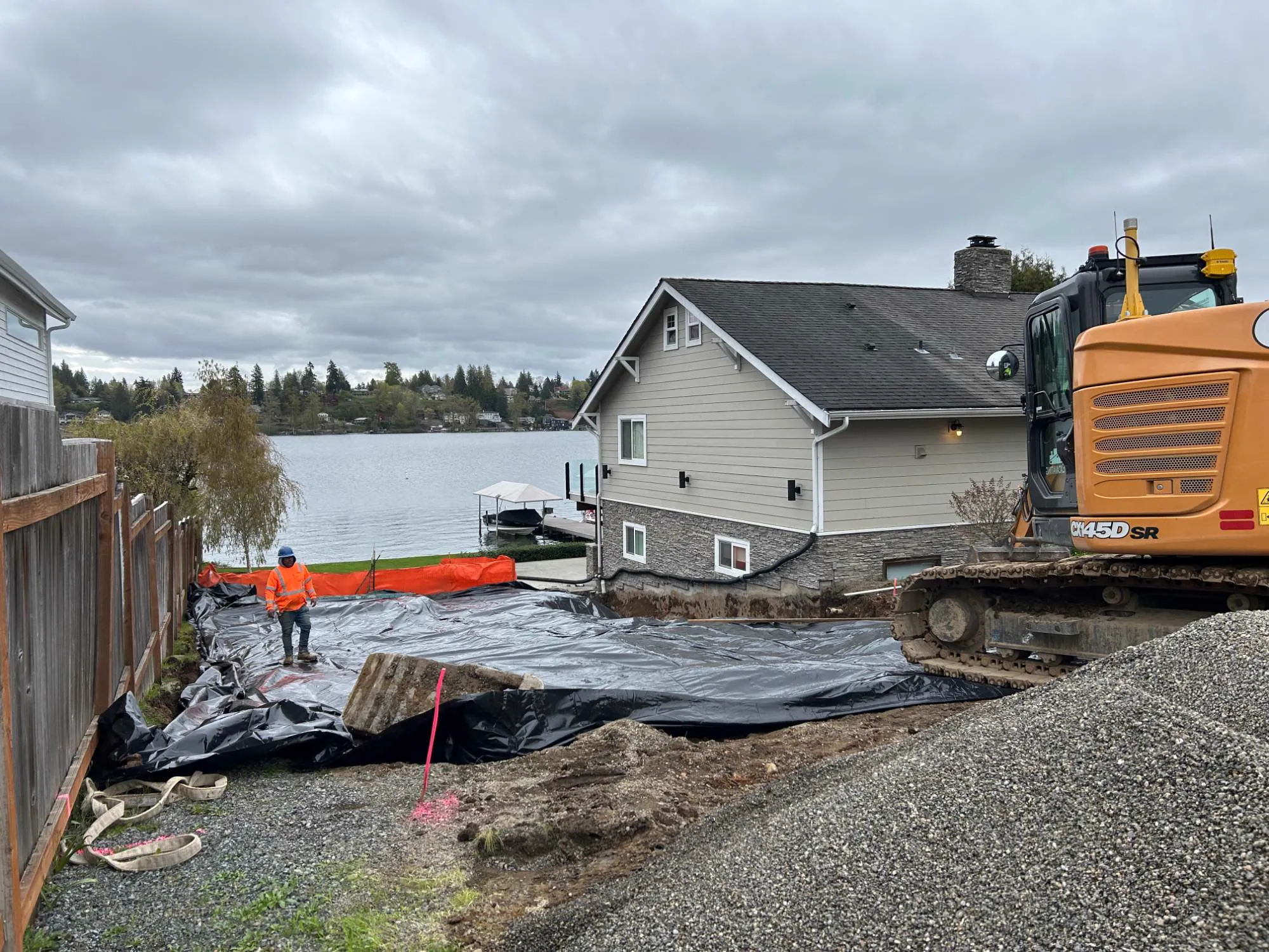 During: site prep on the lakefront lot, with an excavator, gravel and poly sheeting