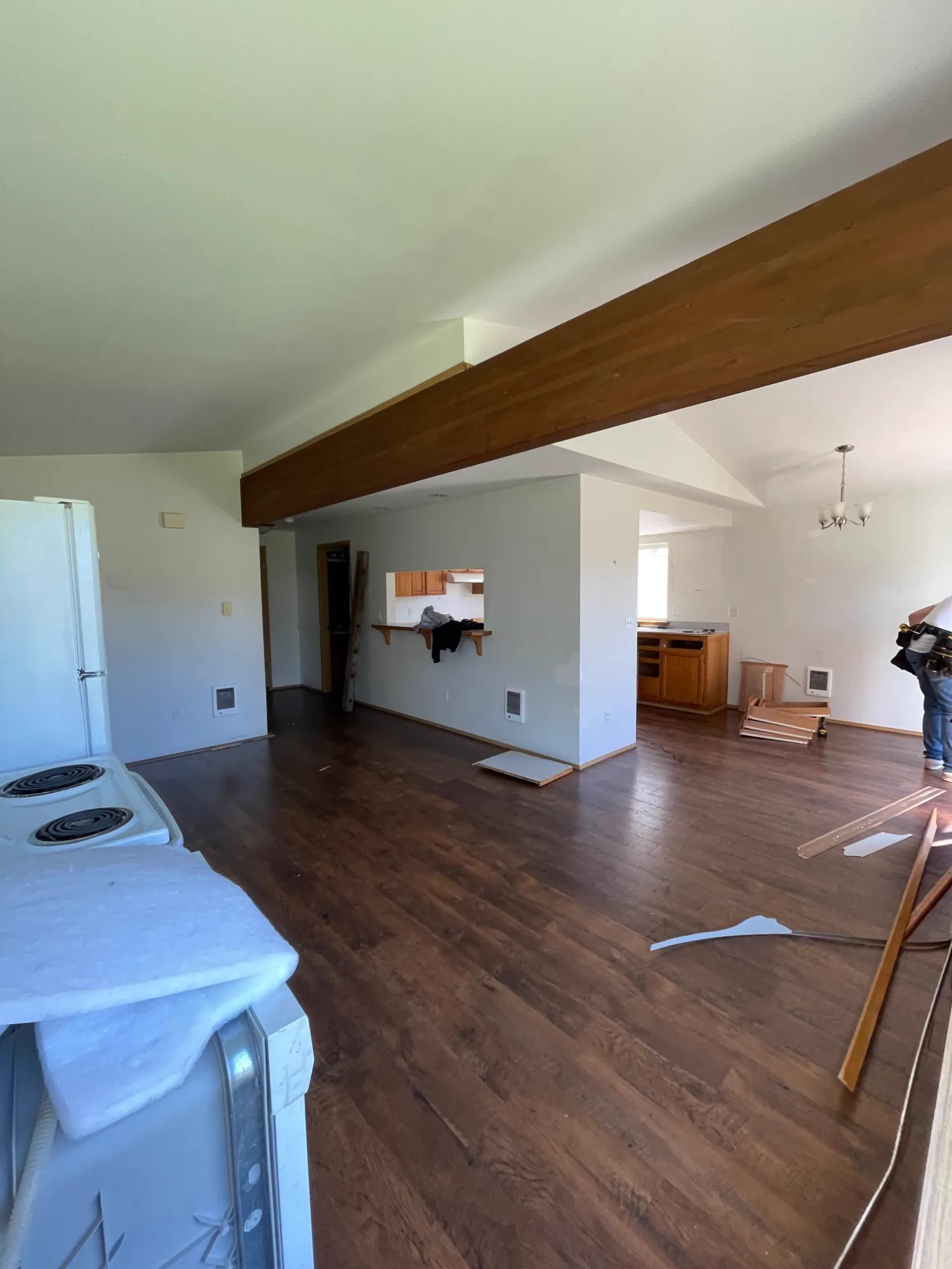 Before: living area with dark floors, stained beam and walled-off kitchen