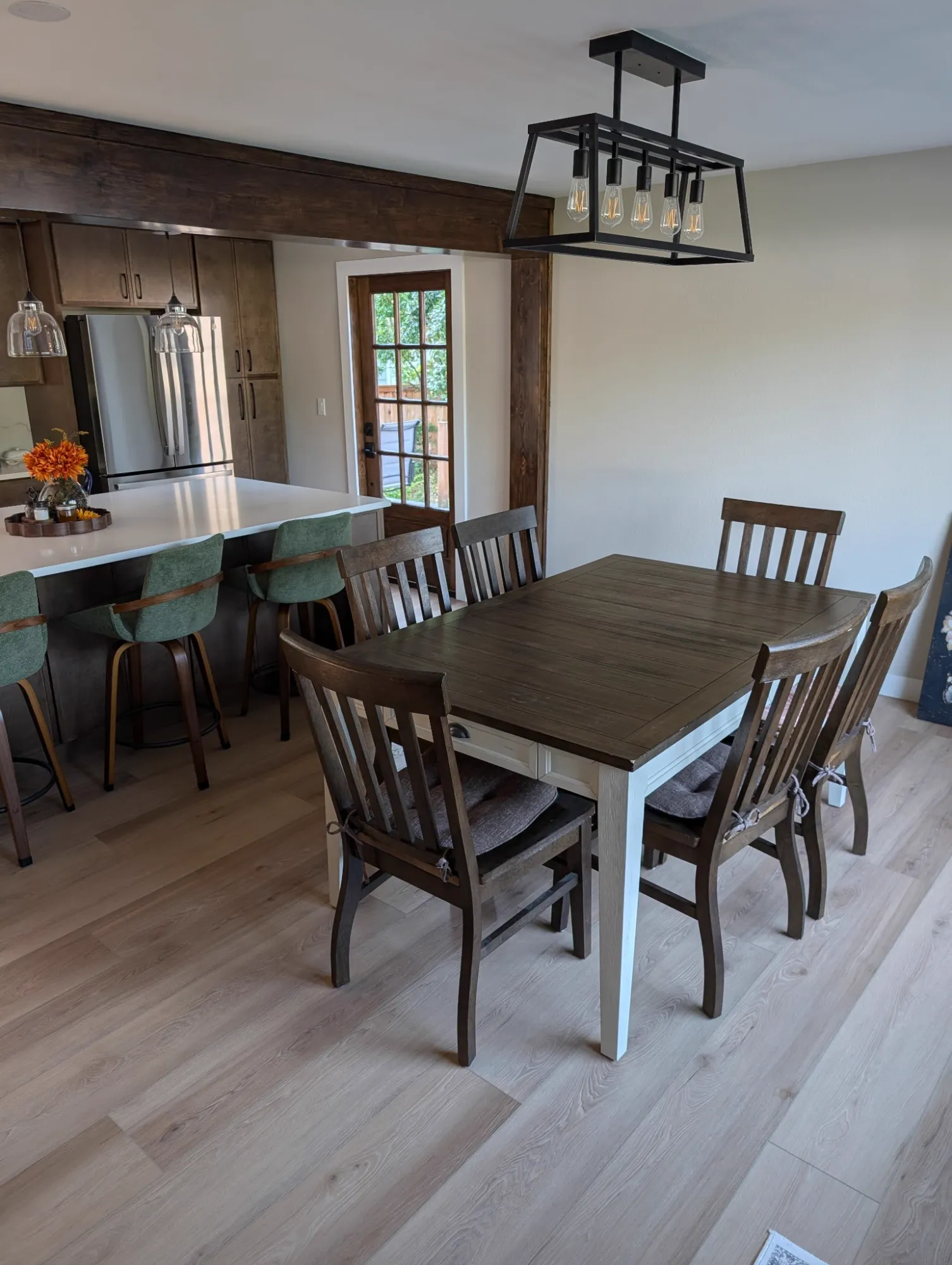 Dining area with a black cage chandelier next to the kitchen island