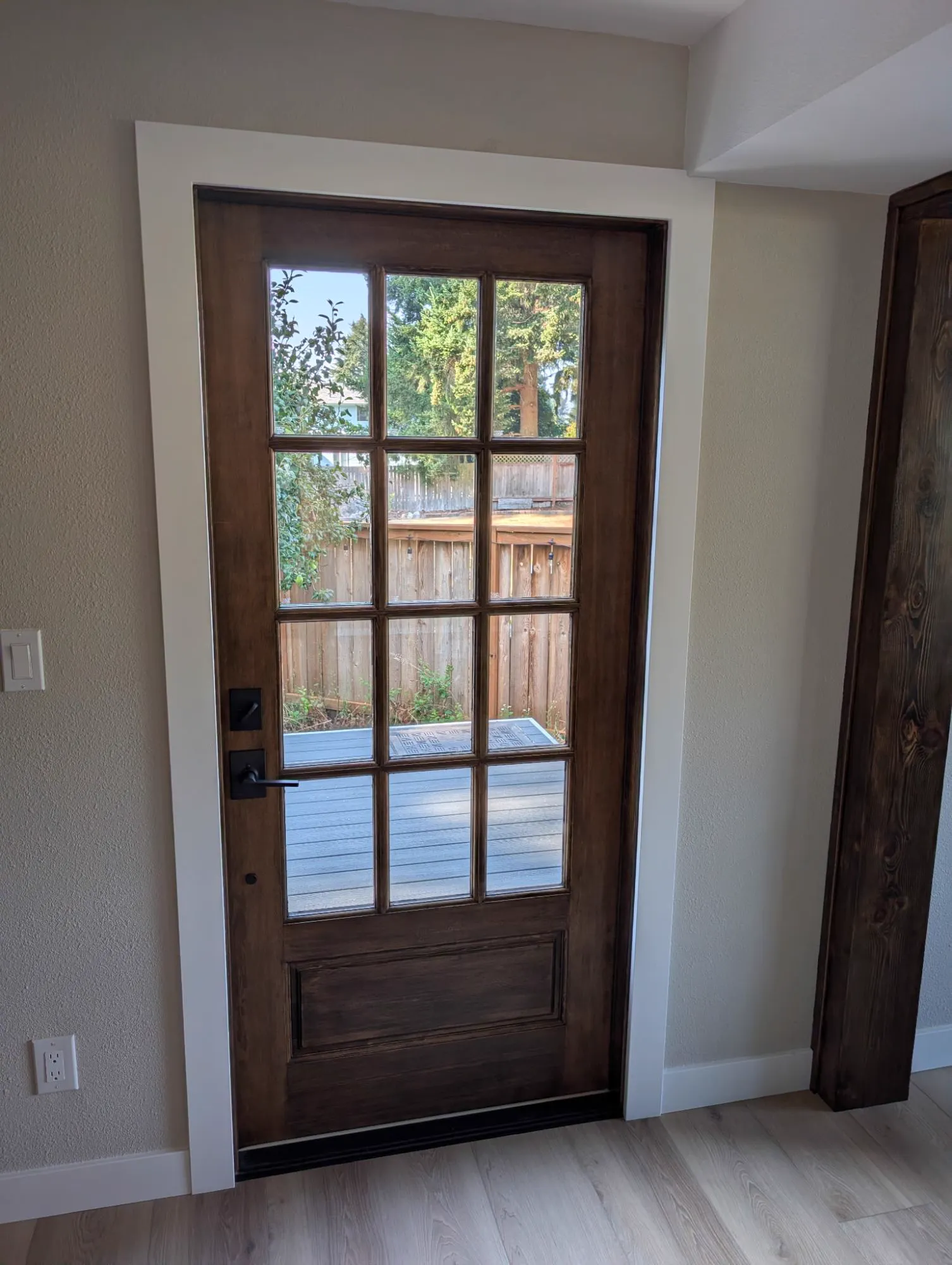 Stained wood divided-light door opening onto a new deck