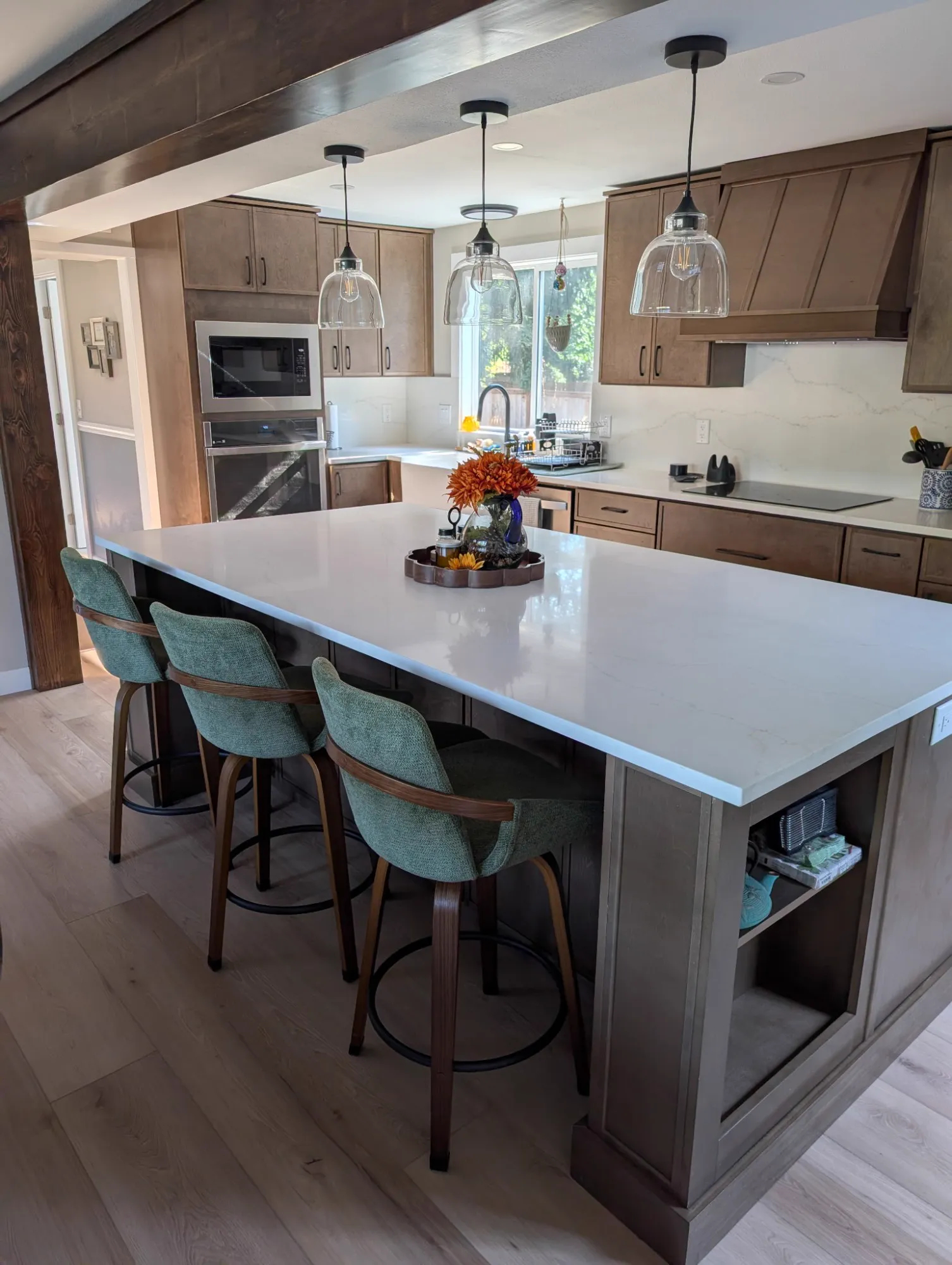 Kitchen island with green stools under glass pendant lights