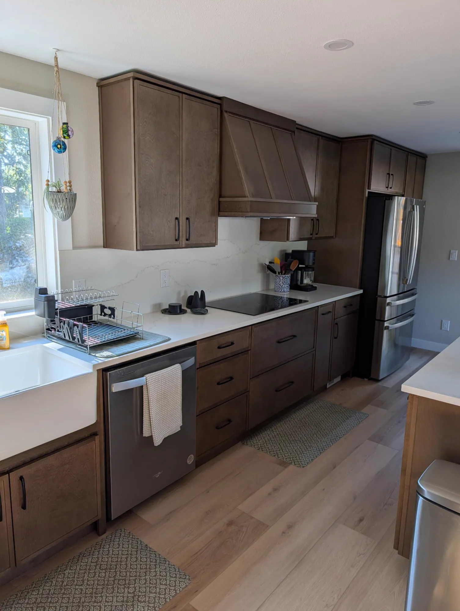 Cabinet run with induction cooktop, wood range hood and quartz backsplash