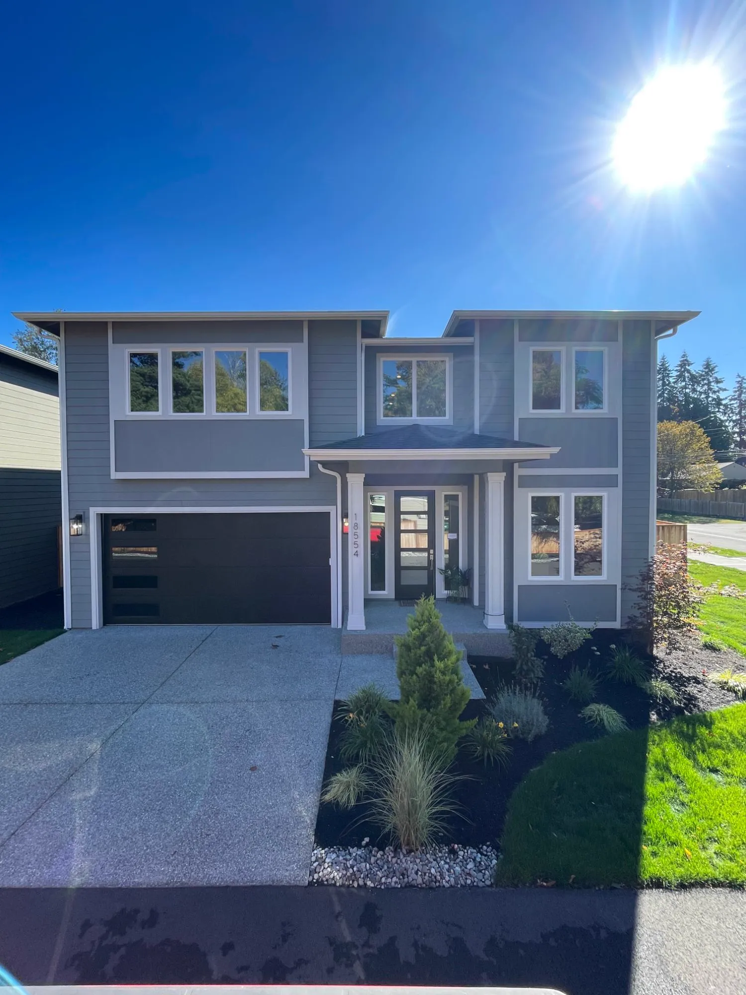 Front of the new Stone Ave home: grey lap siding, white trim, covered entry and black garage door
