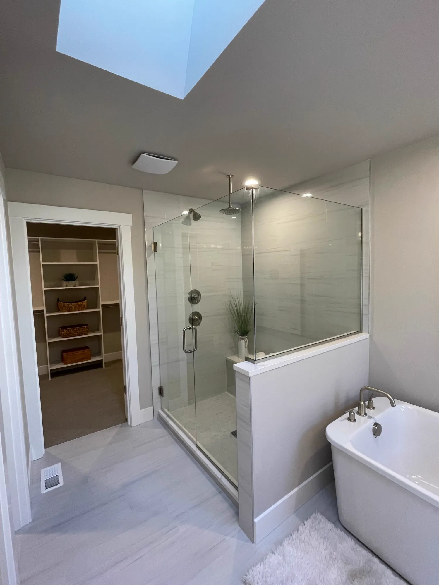 Frameless glass shower with a rain head and tile bench, next to the walk-in closet